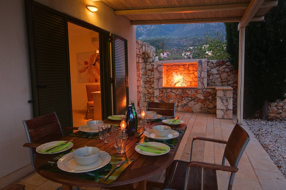 An outdoor dining area with a stone wall and a fire feature.