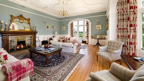 A spacious living room with a fireplace, comfortable seating, and a large mirror. - Balmule House (Dunfermline)