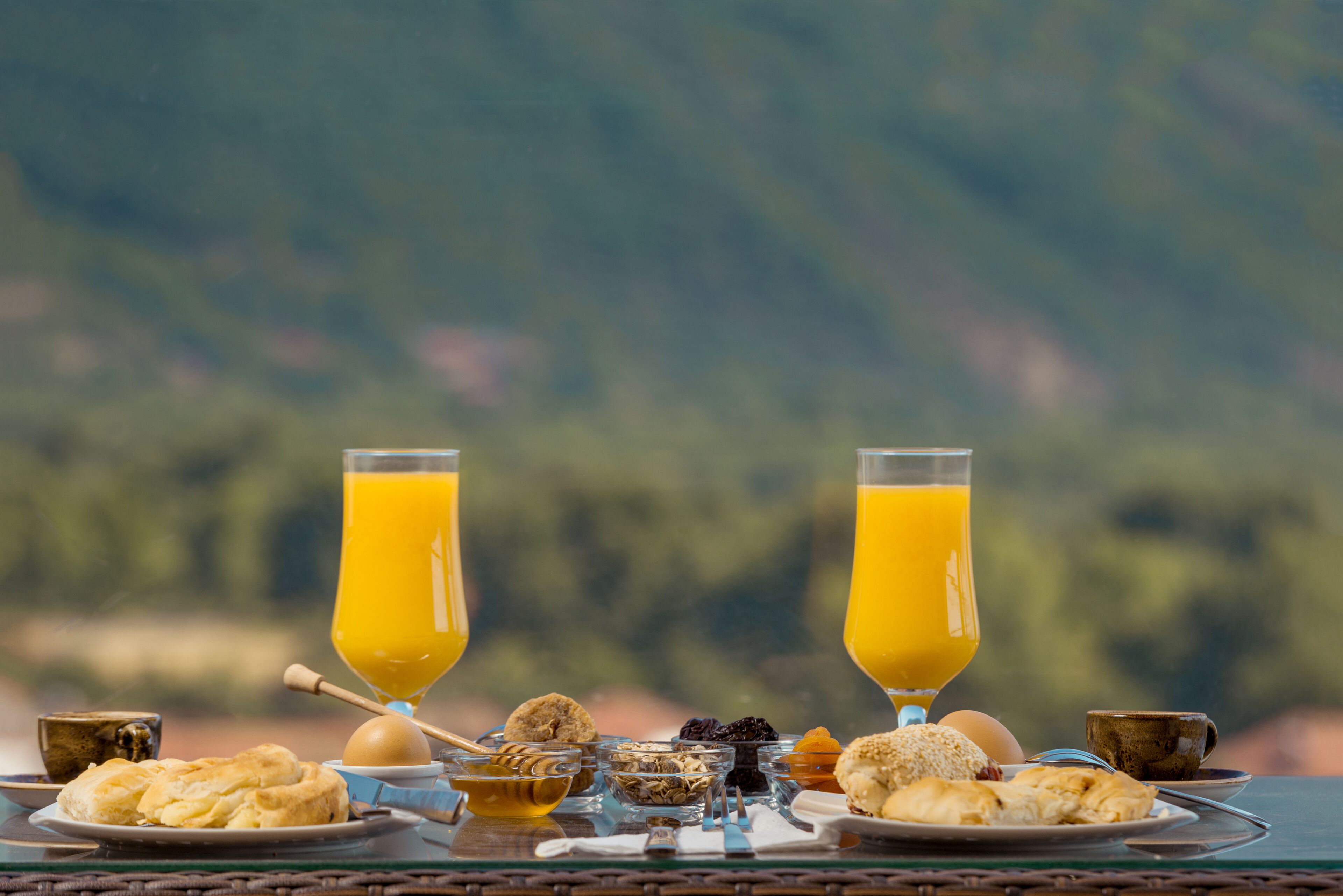 Una mesa de desayuno con varios pasteles, un vaso de jugo de naranja y una taza de café.