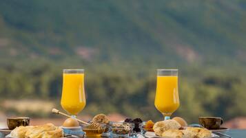 Una mesa de desayuno con varios pasteles, un vaso de jugo de naranja y una taza de café.