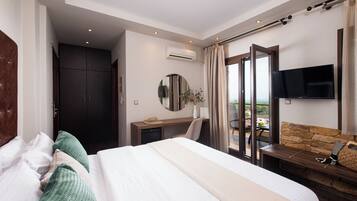 A hotel room with a large bed, a desk, a TV, and a balcony with a view.