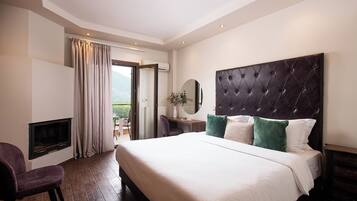 Habitación de hotel con una cama grande, chimenea, escritorio y vistas al exterior.