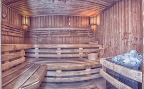 Una sauna de madera con bancos y un calentador de piedra.