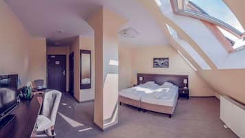 A modern hotel room with a large bed, a TV, a desk, and a chair.