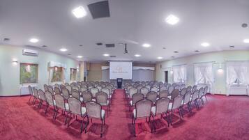 A conference room with rows of chairs, a projector screen, and a red carpet.