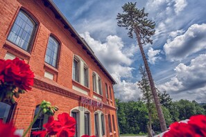 A red brick building with arched windows and a sign that reads "RESTAURACJA". - Hotel Niemcza SPA (Niemcza)