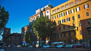 Vista de la calle con edificios de varios pisos, coches aparcados y una línea de tranvía.