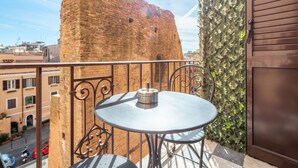 Un balcón con una mesa y sillas de metal redondas, un muro de ladrillo y una pared cubierta de follaje verde.
