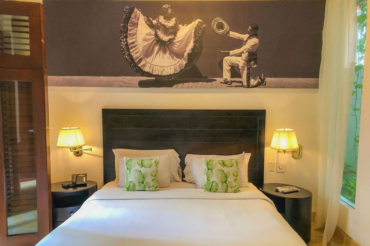 Une chambre d’hôtel avec un grand lit, deux lampes de chevet, un téléphone et un tableau au mur.