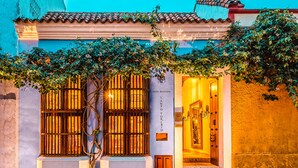 L’entrée d’un hôtel, avec un toit recouvert de tuiles, une porte en bois et une enseigne indiquant « HÔTEL DE CHARME ».