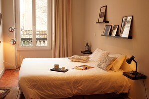 A neatly made bed with a tray of breakfast items, a bedside lamp, and a window with curtains. - Decoh Studio Dragon (Marseille)