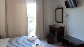 Hotelkamer met een bed, een bureau, een stoel, een televisie en een raam met gordijnen.