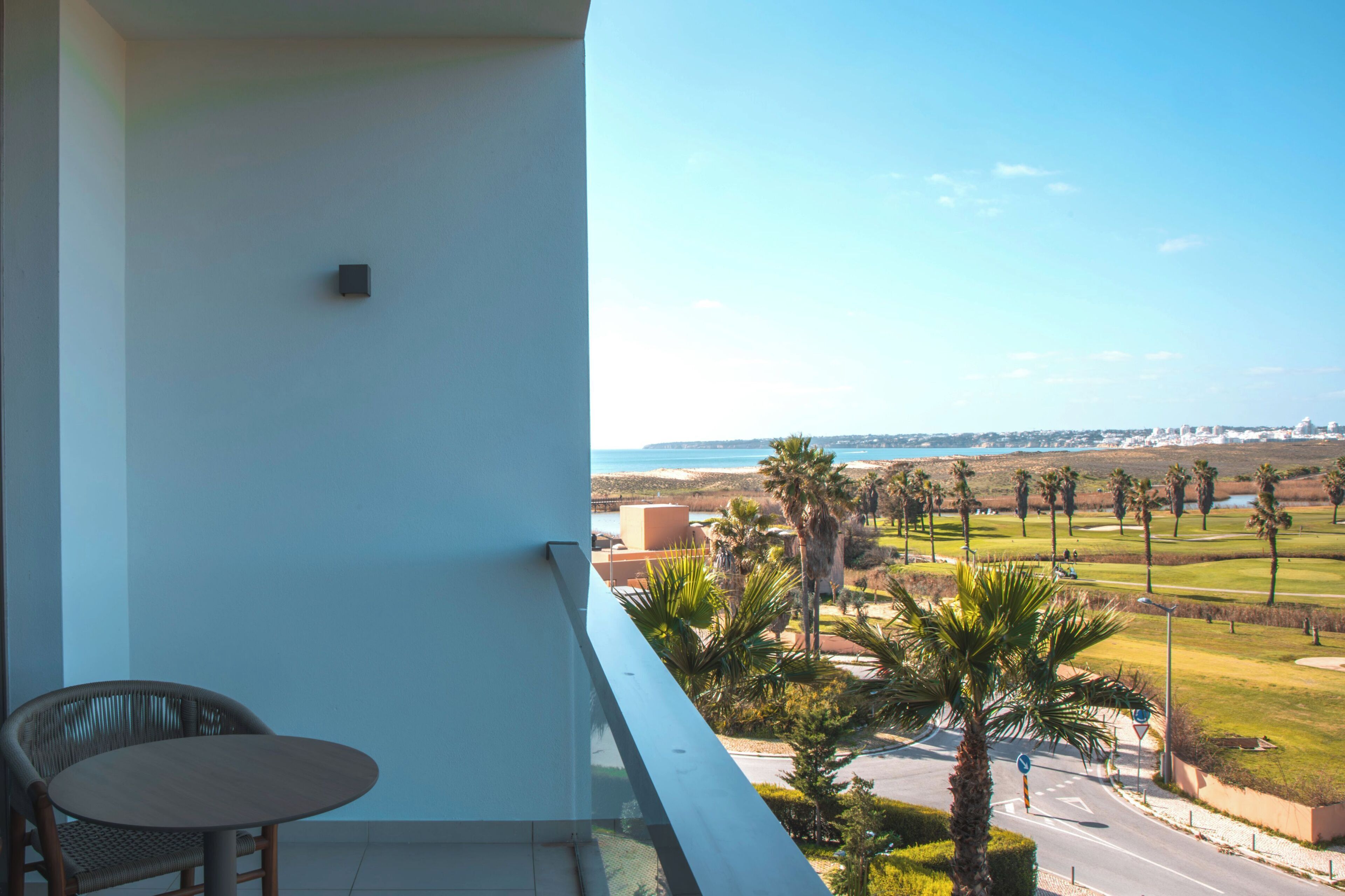 Un balcon offrant une vue sur un terrain de golf et sur le paysage urbain au loin.