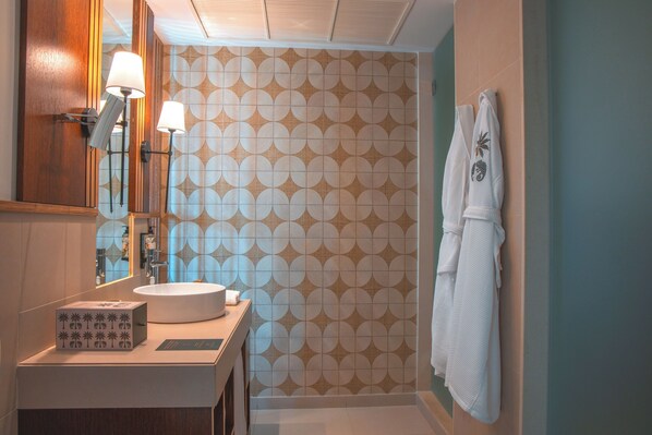 A bathroom with a round sink, two wall-mounted lamps, a towel rack with a towel, and a patterned wall. - Wine & Books by the sea (Albufeira)