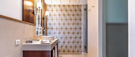 Une salle de bain moderne avec un meuble-lavabo en bois, un miroir, un porte-serviettes et un mur décoré d’un motif.