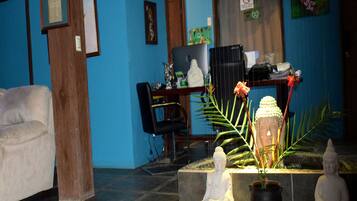 A room with a blue wall, a desk with a computer, and two Buddha statues.