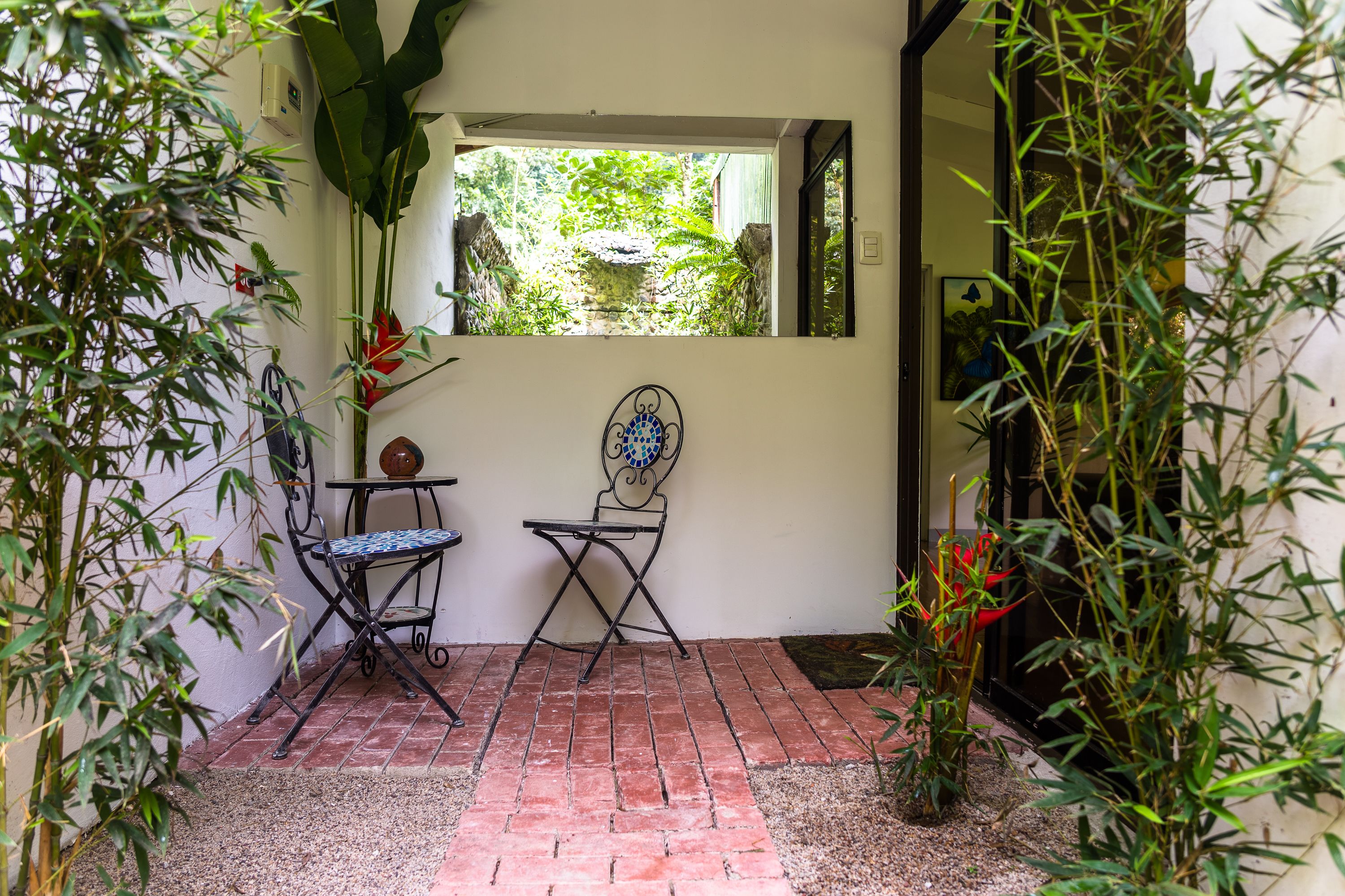 A patio with a brick floor, two metal chairs, and a table.