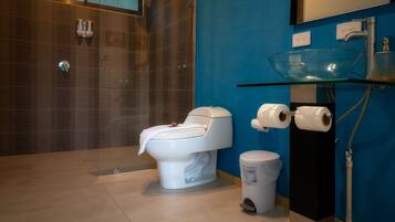A modern bathroom with a glass bowl sink, a toilet, and a shower area.