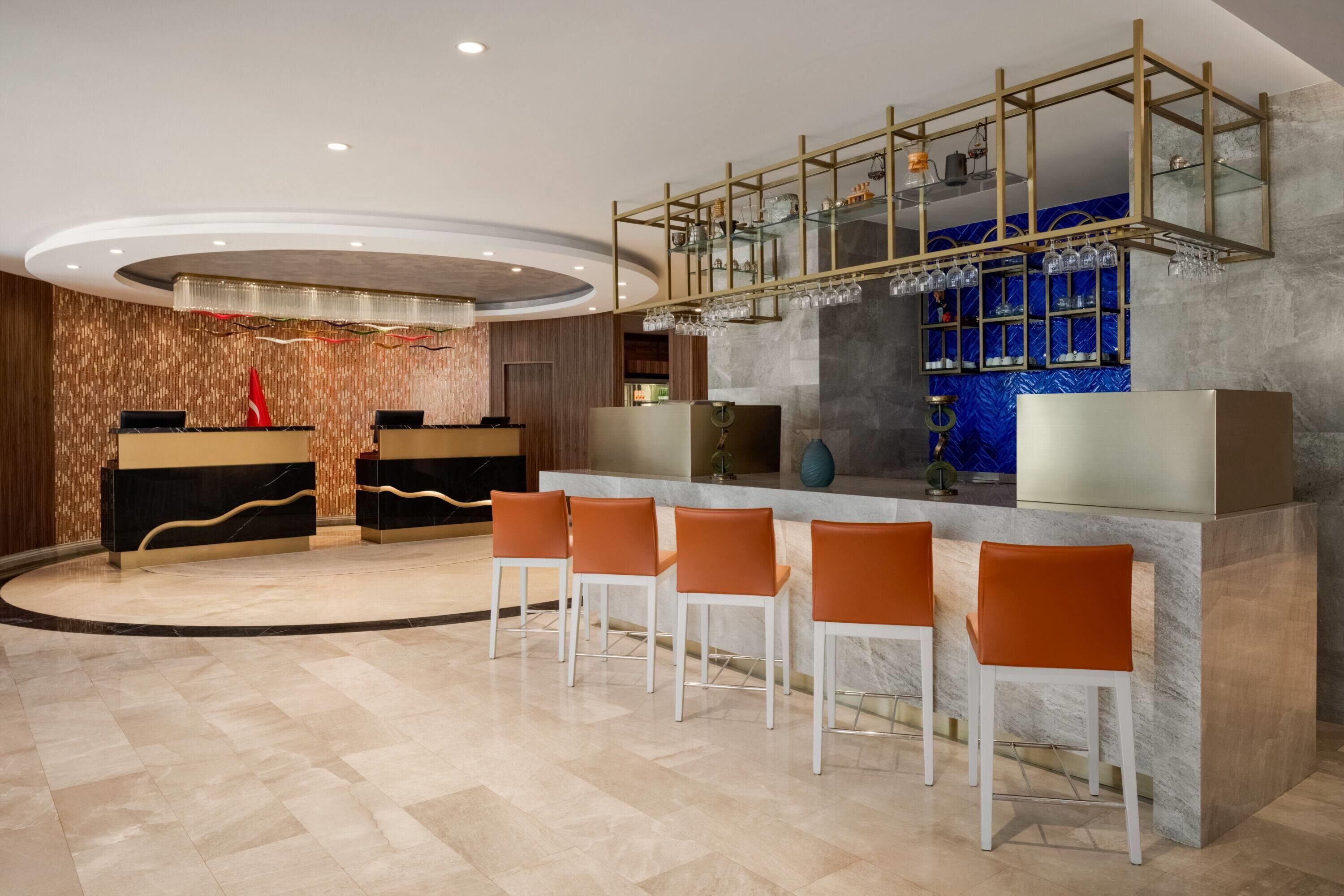 A modern bar area with a marble countertop, bar stools, and a decorative ceiling.