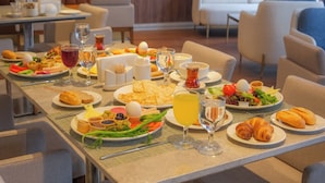 A dining area with multiple tables set with breakfast plates, including croissants, eggs, and salads. - Ramada Encore by Wyndham Konya Karatay (Konya)