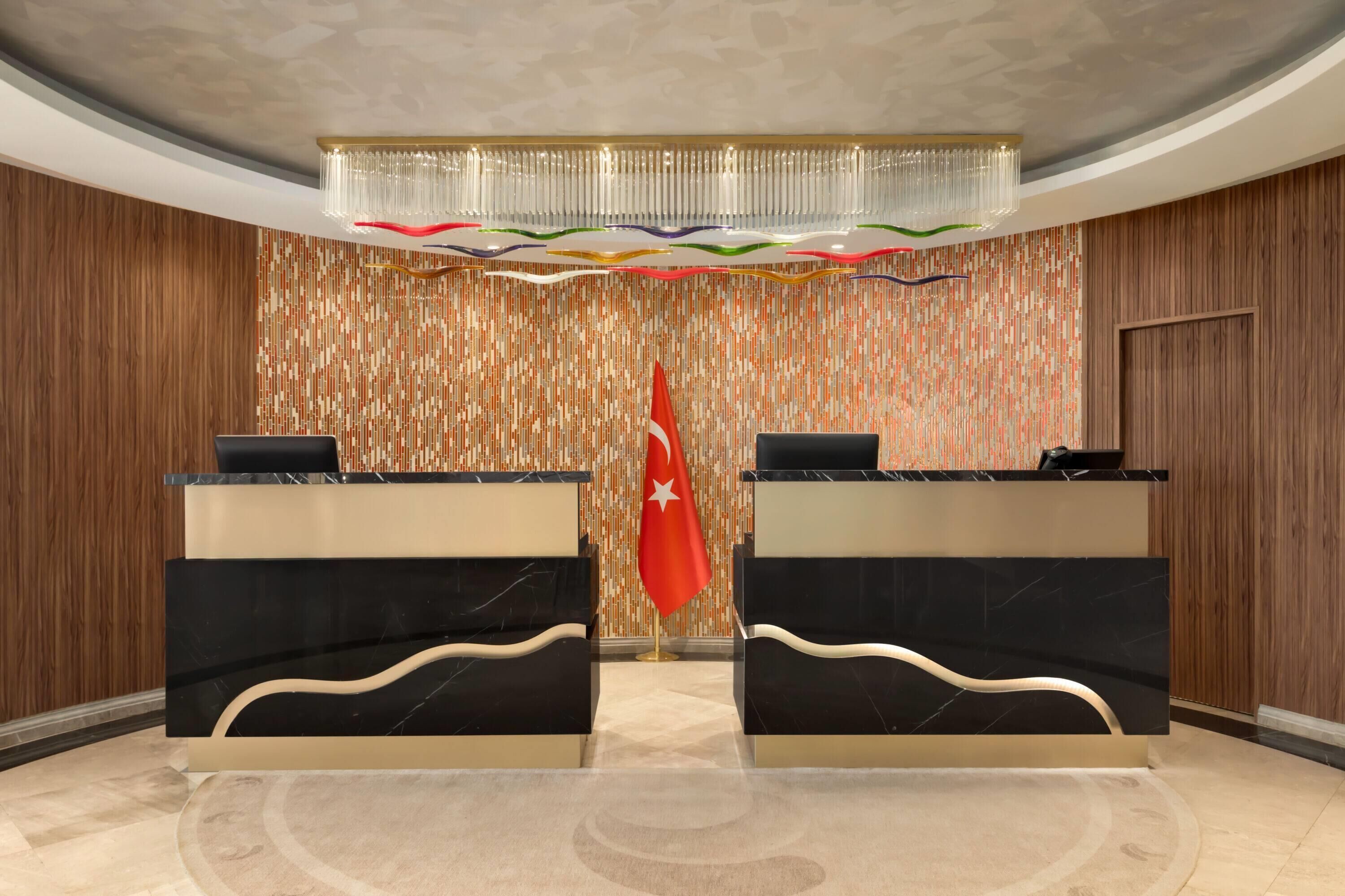A reception area with two black marble counters, a red flag, and a patterned wall.