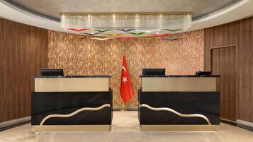 A reception area with two black marble counters, a red flag, and a patterned wall.