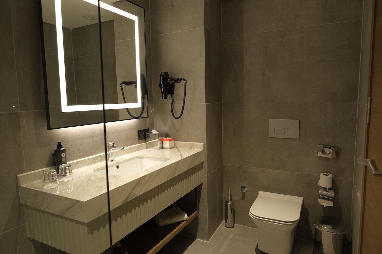 A modern bathroom with a large mirror, a sink, a toilet, and a shower.
