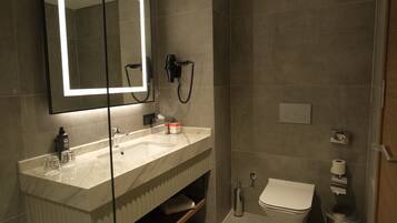 A modern bathroom with a large mirror, a sink, a toilet, and a shower.