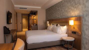 Una habitación de hotel moderna con una cama grande, una mesa redonda y un televisor montado en la pared.
