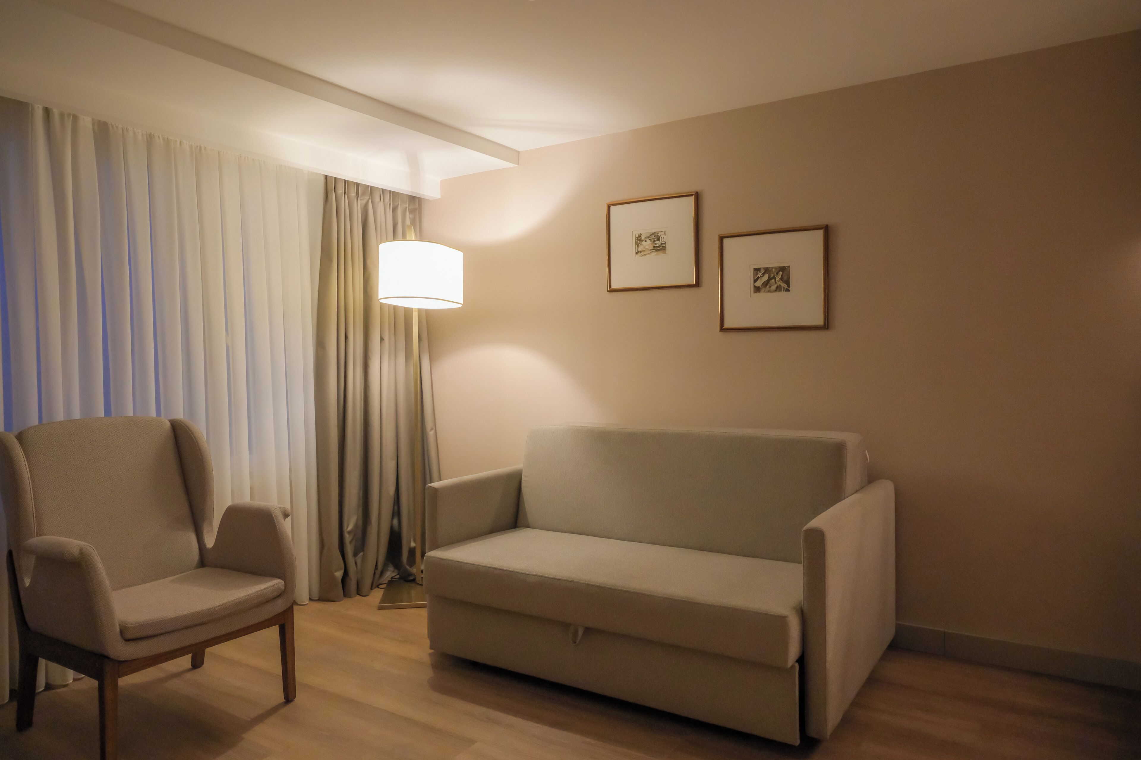 A living room with a sofa, armchair, and a lamp.