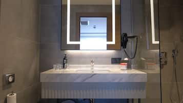 Een moderne badkamer met een grote spiegel, een wastafel, een haardroger en een douche.