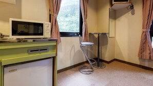 Une chambre compacte dotée d’une kitchenette comprenant un four à micro-ondes, un petit réfrigérateur et un tabouret de bar.