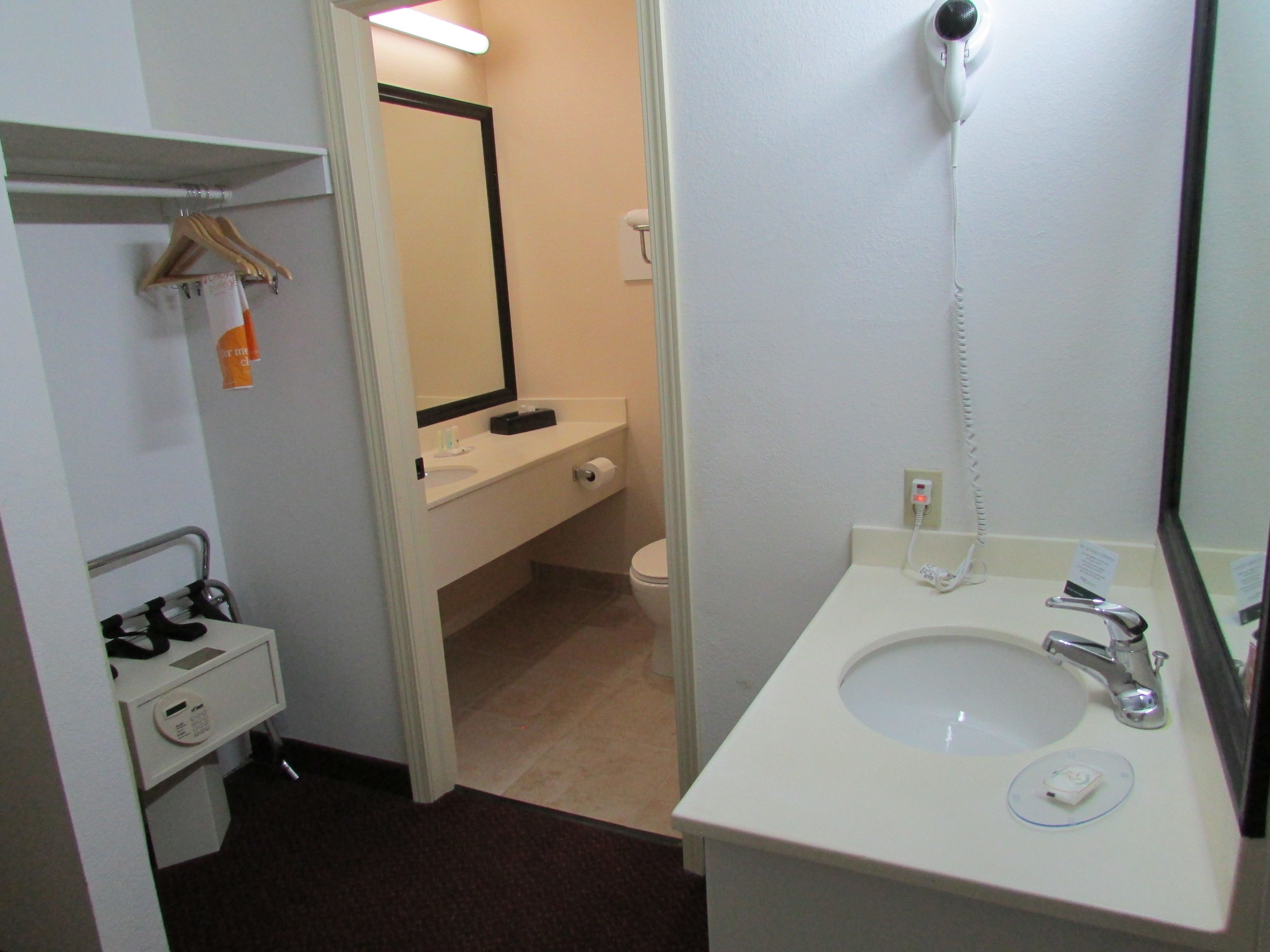 A hotel bathroom with a white sink, a mirror, a towel rack, a toilet, and a shower.