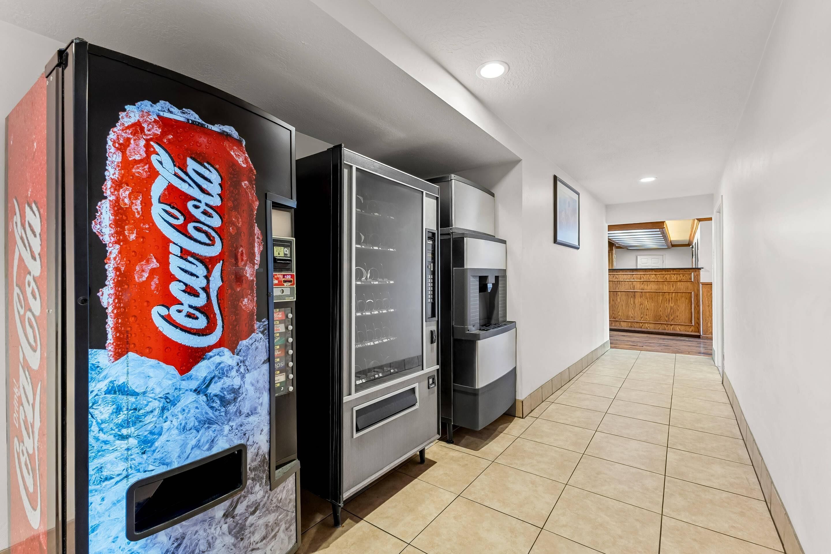 A hallway with vending machines, a refrigerator, and a kitchen area.