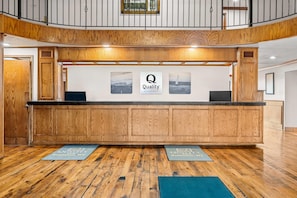A reception desk with wooden paneling, a 'Quality by Choice Hotels' sign, and a view of the lobby. - Quality Inn Evanston near Wyoming Downs (Evanston)