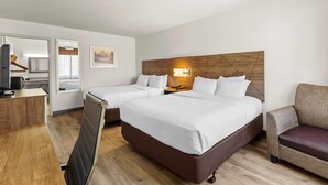 Ein Hotelzimmer mit zwei Betten, einem Schreibtisch, einem Sessel und einem Fernseher.