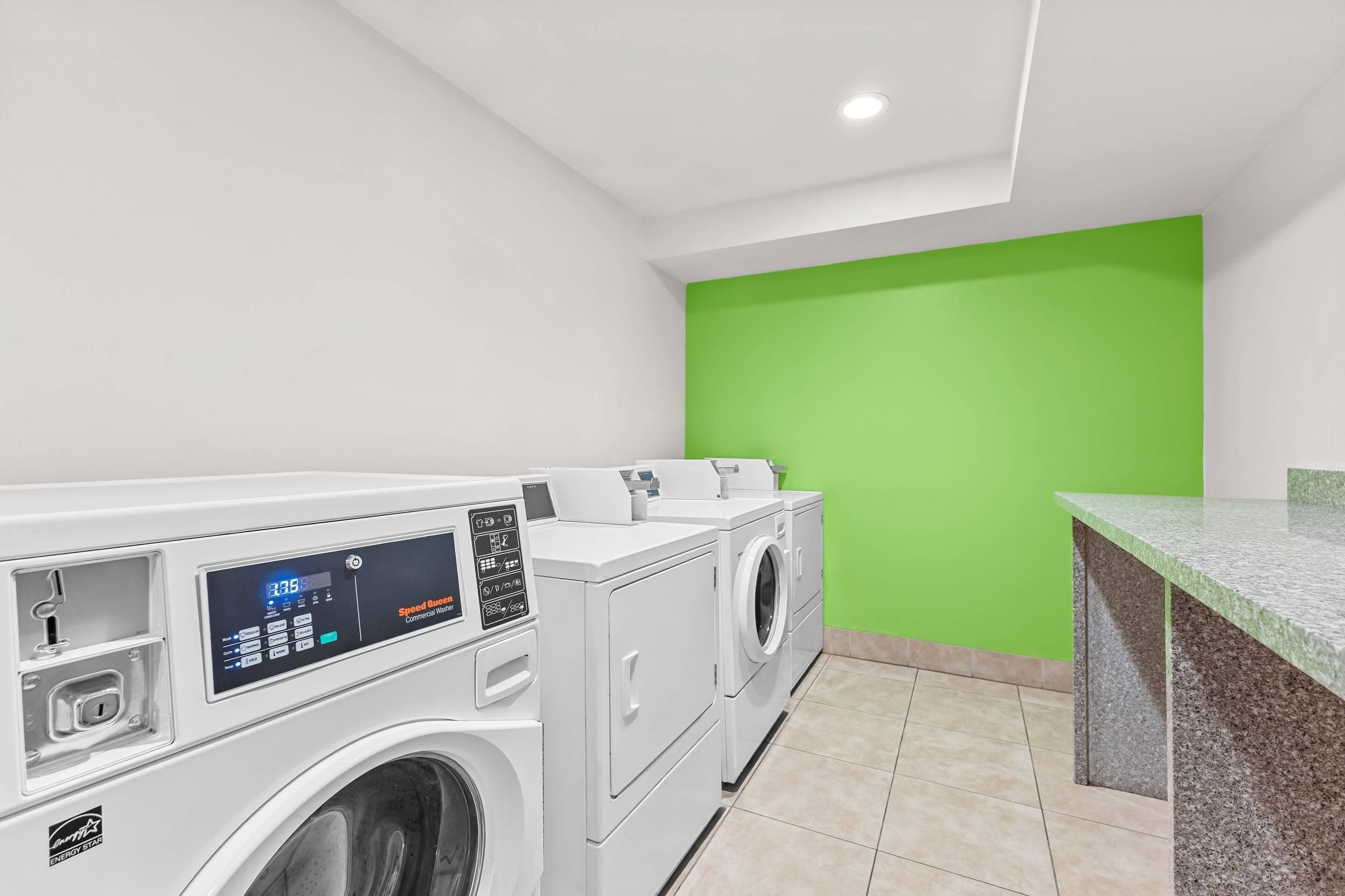 A laundry area with a washing machine, dryer, and a green wall.