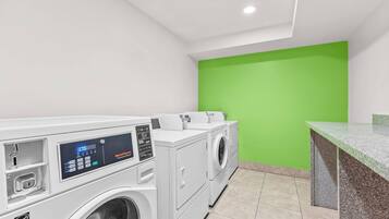 A laundry area with a washing machine, dryer, and a green wall.