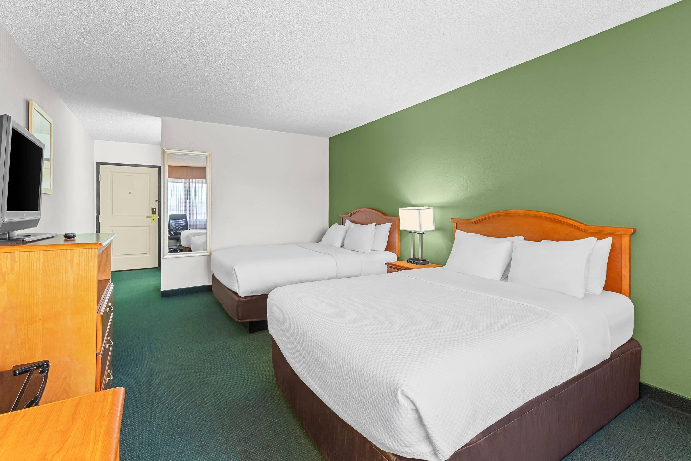 A hotel room with two beds, a TV, a desk, and a wardrobe.