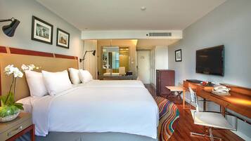 A hotel room with two beds, a desk with a chair, a TV, and a bathroom visible through an open door.