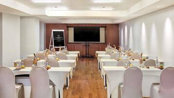 A conference room with tables set for a meeting, a projector screen, and a whiteboard.