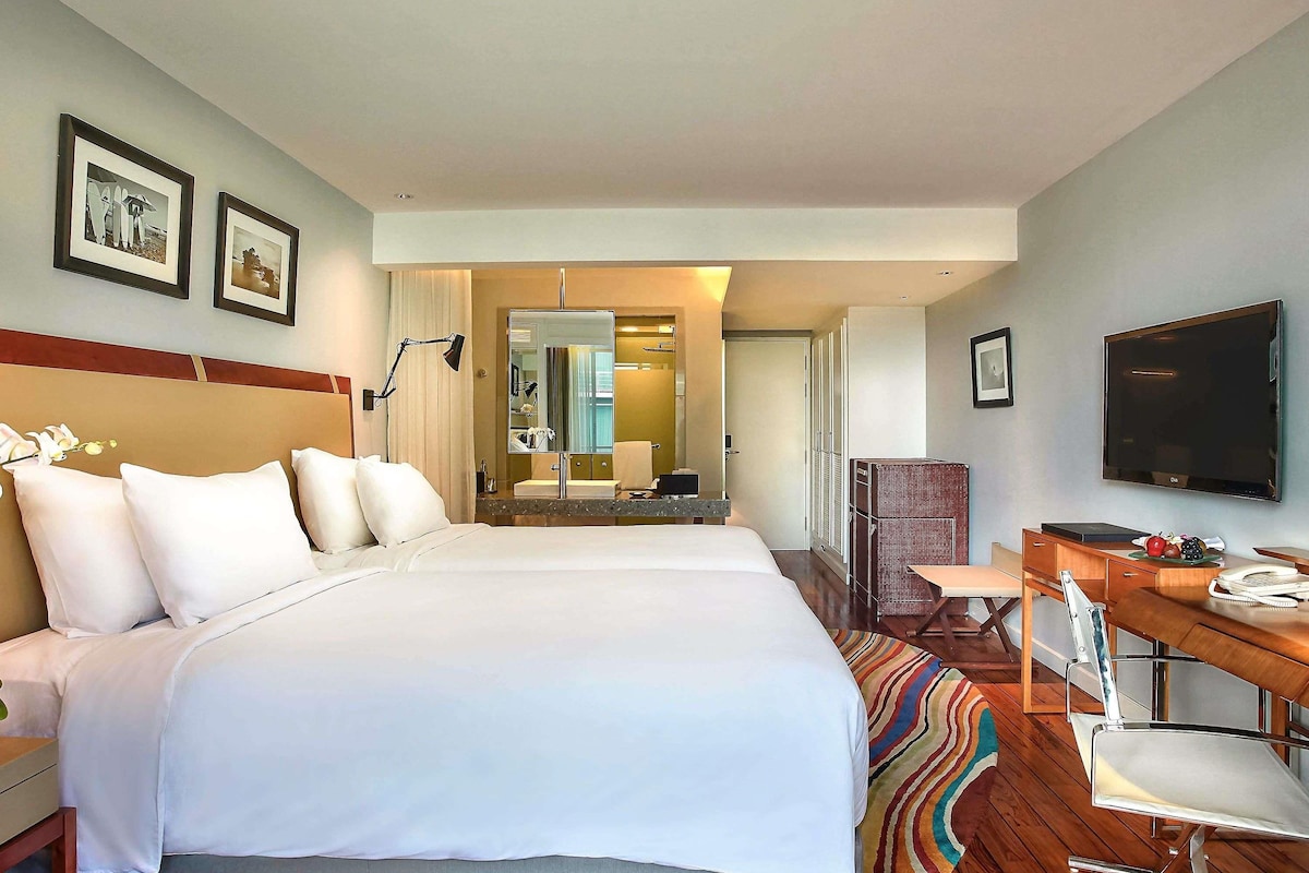 Ein Hotelzimmer mit einem großen Bett, einem Schreibtisch mit Stuhl, einem Fernseher und einem Spiegel.