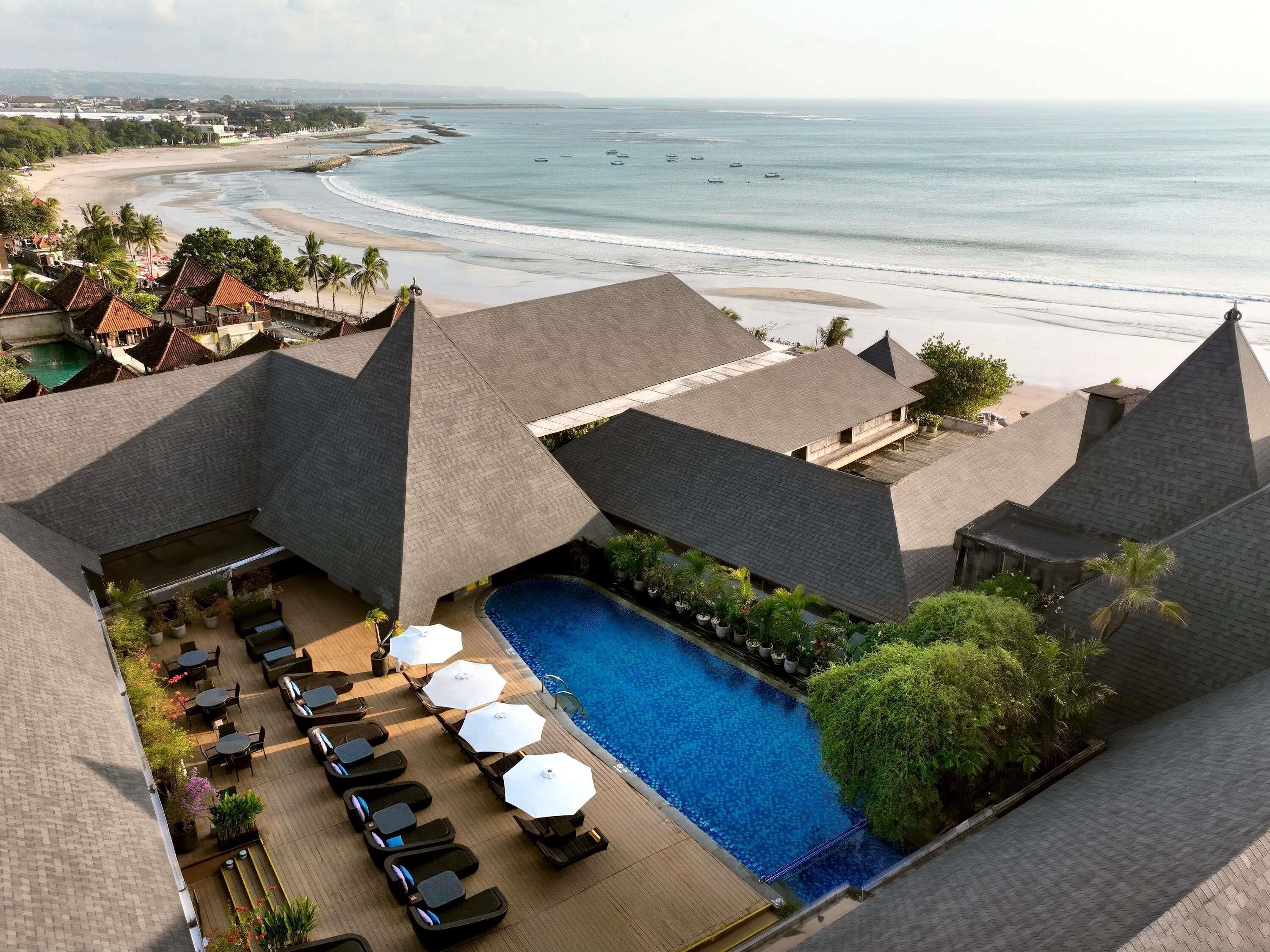 A resort with a pool area, lounge chairs, and a view of the beach and ocean.