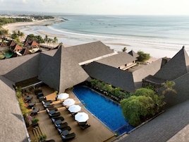 A resort with a pool area, lounge chairs, and a view of the beach and ocean.