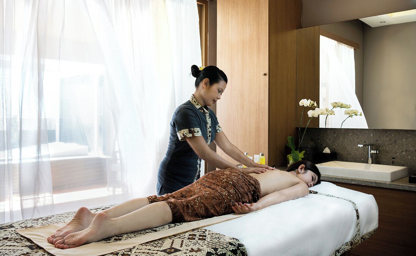 Sesión de terapia de masajes en un moderno spa con un espejo grande, un lavamanos y una ventana con cortinas translúcidas.