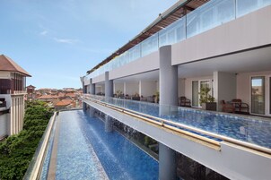 A modern hotel with a glass balustrade overlooking a swimming pool.