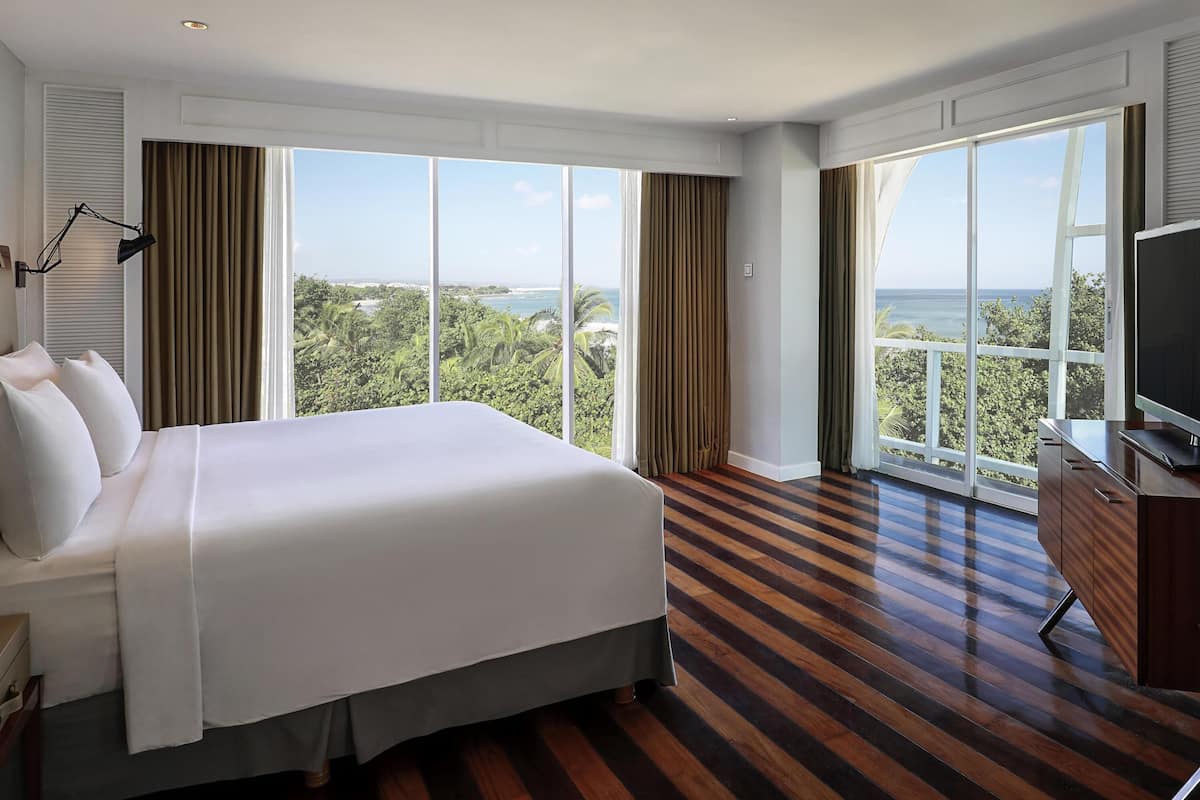Une chambre d’hôtel avec un grand lit, une télévision et une vue sur l’océan.