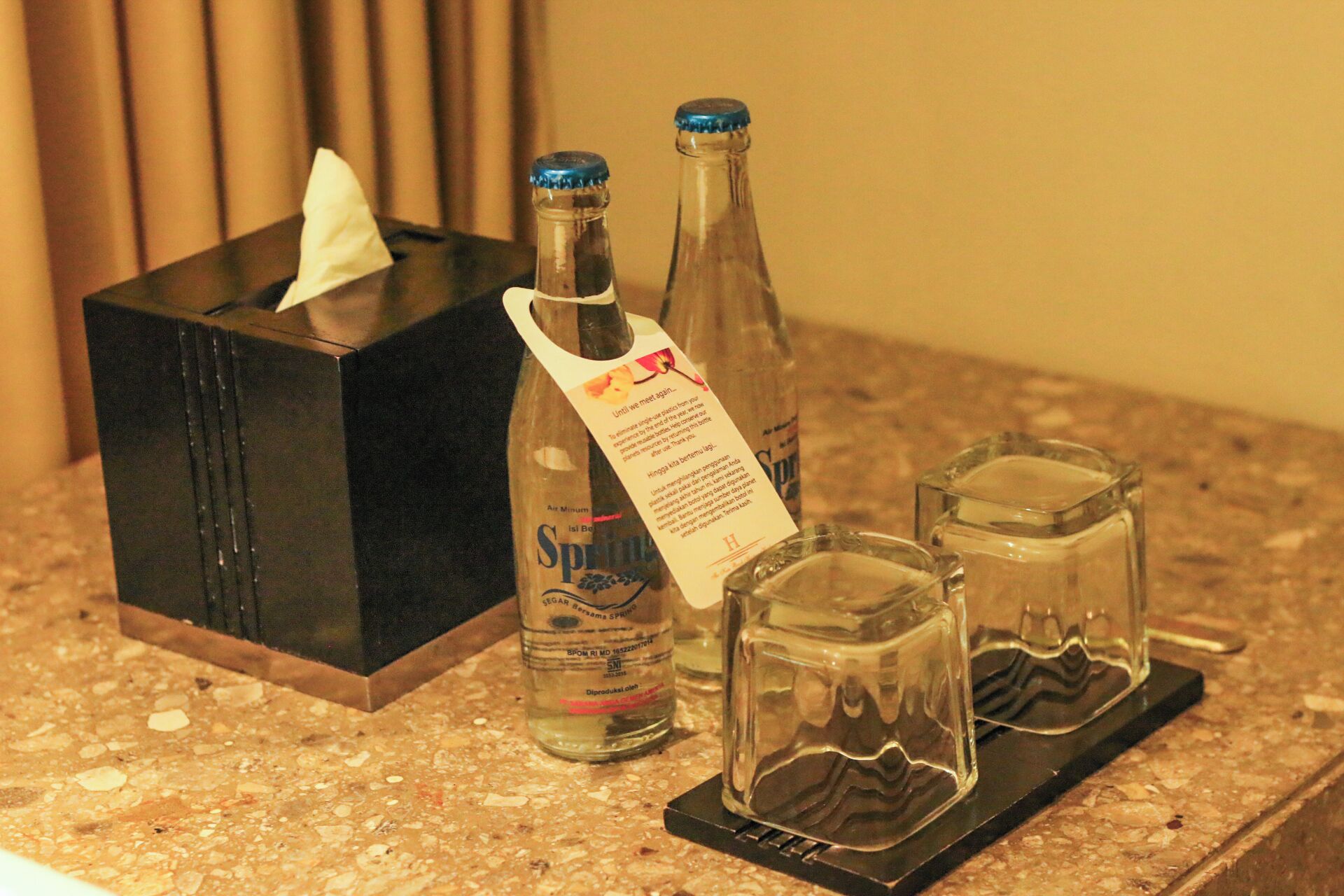 Une boîte de mouchoirs, deux bouteilles et deux verres à shooter sont posés sur un comptoir.
