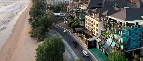 A coastal hotel with a beachfront view, multiple floors, and a restaurant on the ground level.