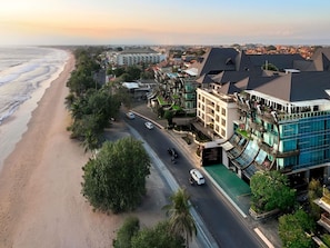 A coastal hotel with a beachfront view, multiple floors, and a restaurant on the ground level.
